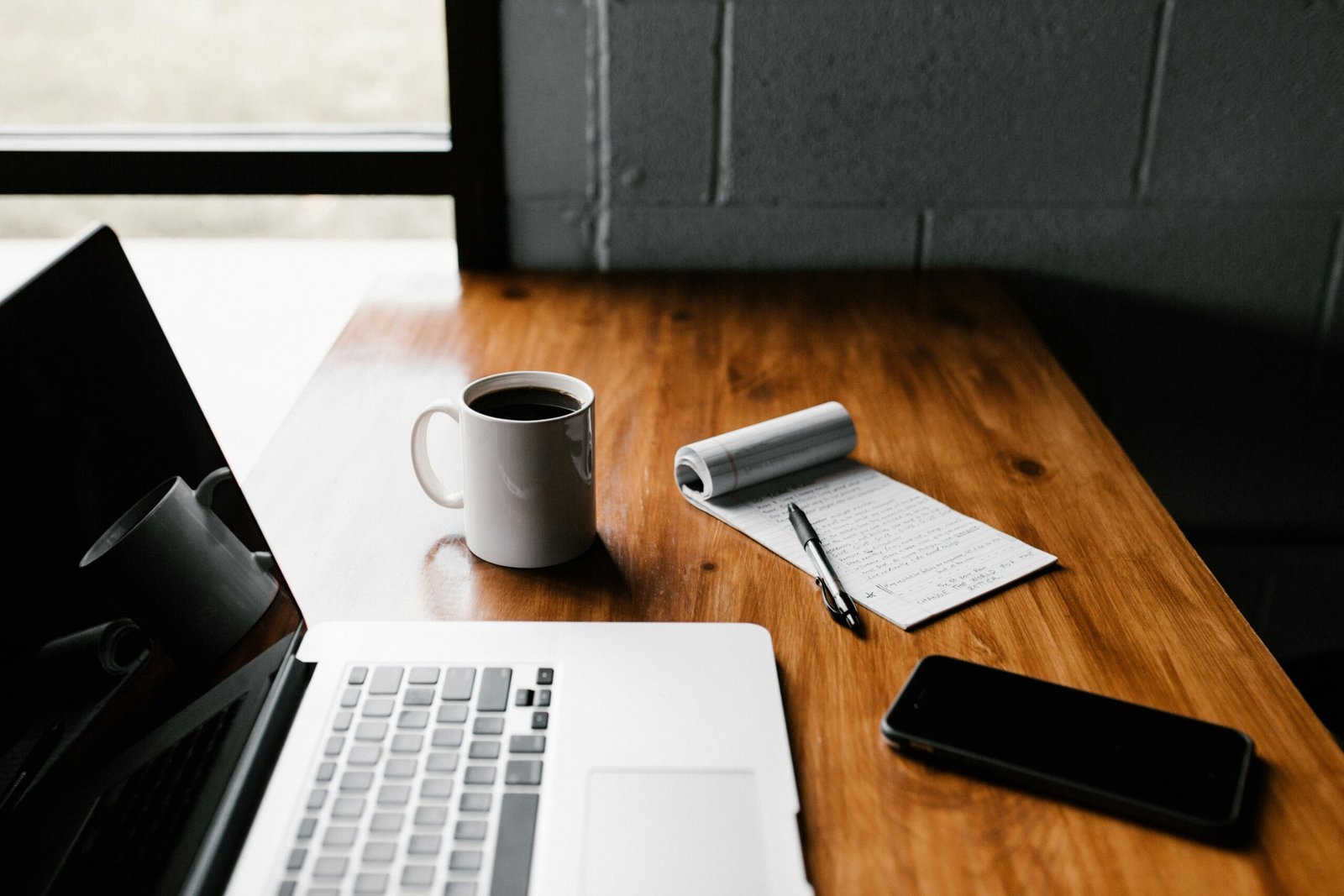 Un bureau moderne en bois, café à la main, prêt à écrire un article de blog sur comment rédiger des articles de blog généalogiques captivants.